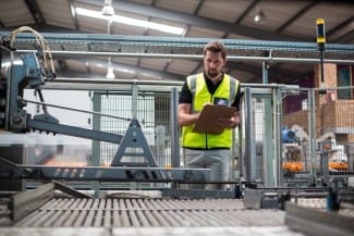 Attentive factory worker maintaining record on clipboard in factory