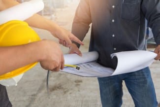 Engineer and Architect working at Construction Site with blueprint