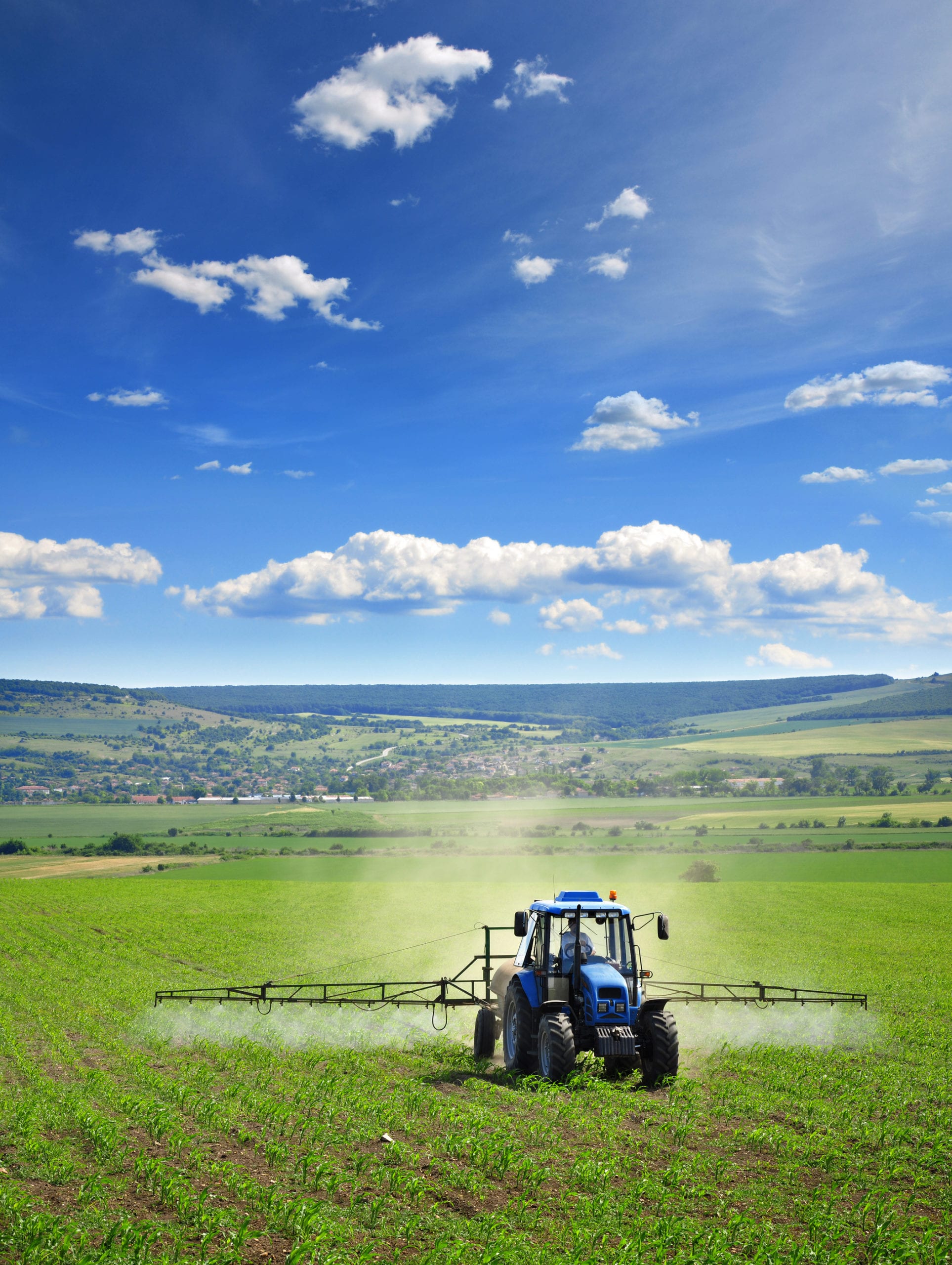 Farming tractor plowing and spraying on field vertical