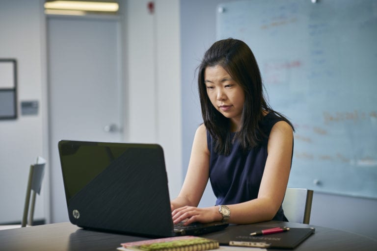 Female student close up in business casual working on computer