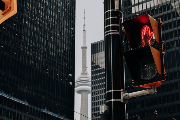 Traffic light with red color and TV tower between skyscrapers